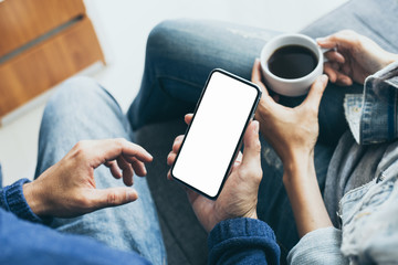 Mockup image blank white screen cell phone.men hand holding texting using mobile on sofa at home.background empty space for advertise text.people contact marketing business and technology