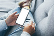 © panitan - Mockup image blank white screen cell phone.man hand holding texting using mobile on sofa at home.background empty space for advertise text.people contact marketing business,technology