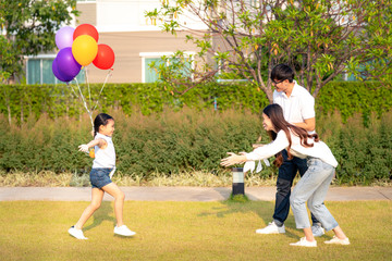 Wall Mural - Asian daughter run with balloon on hand to her mother and her father