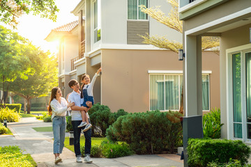 Wall Mural - Beautiful family portrait smiling outside their new house with sunset