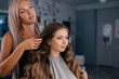 © Andrii Lysenko - Stylish woman parekmacher correct the hairstyle of a young girl in a beauty salon in front of a mirror