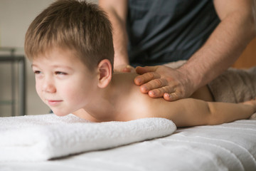 Wall Mural - Boy toddler relaxes from a therapeutic massage. Physiotherapist working with patient in clinic to the back of a child