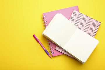 Stylish notebooks and pen on yellow background, flat lay. Space for text