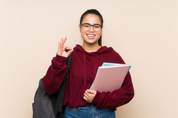 Young student Asian girl woman over isolated background showing an ok sign with fingers