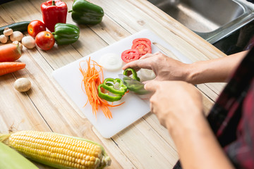 Close-up man cooking and slicing fresh vegetables on a rustic kitchen worktop, healthy eating concept, flat lay