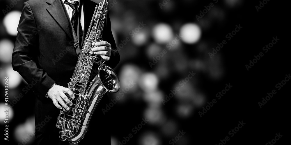 Playin' sax isolated at the left border of a black background (black and white) - obrazy, fototapety, plakaty 