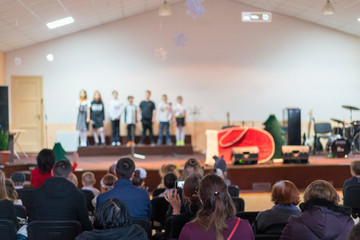 Children at school perform on stage in front of parents. Young talents on stage. blurry