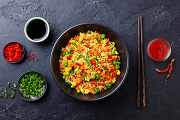 Wall Mural - Asian fried rice with egg and vegetables. Dark stone background. Top view.