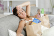 exhausted woman on sofa surrounded by grocery bags