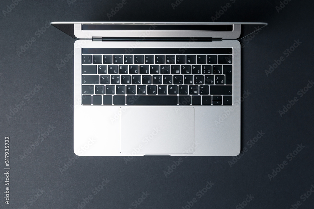 Top view of a modern compact laptop on a dark background. High technology. The laptop screen is open. The concept of a modern gadget. Freelancer's workplace. Black background