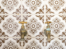 Close-Up Of Faucets On Tiled Wall