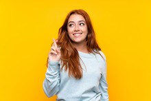 Teenager Redhead Girl Over Isolated Yellow Background With Fingers Crossing And Wishing The Best