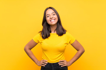 Young brunette girl over isolated background posing with arms at hip and smiling