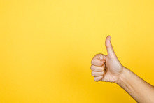 Closeup Of Thumbs Up Symbol On Yellow Background