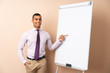 © luismolinero - Young business man over isolated background giving a presentation on white board and pointing it