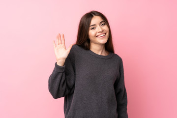 Wall Mural - Young woman over isolated pink background saluting with hand with happy expression