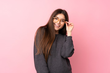 Wall Mural - Young woman over isolated pink background with glasses and happy