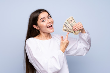 Wall Mural - Young woman over isolated blue background taking a lot of money