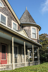 Weathered shingled house with turret and porch and red door in Cape Cod USA