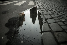 Reflection Of Building In Puddle On Road