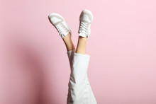 Sneakers On Female Legs On A Colored Background.
