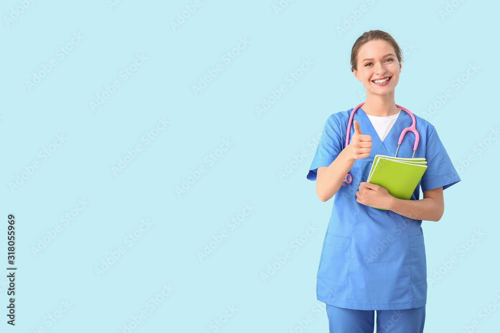 Female medical student showing thumb-up gesture on color background