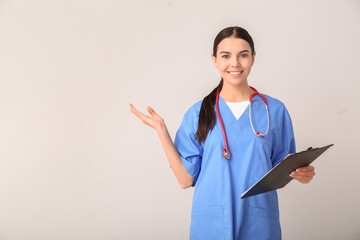 Sticker - Female medical student showing something on light background