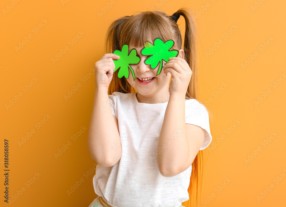 Funny little girl with clover on color background. St. Patrick's Day celebration