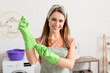 © Pixel-Shot - Young housewife putting on rubber gloves before cleaning flat