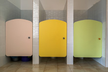 Colorful Toilet Doors In Elementary School Bathroom Interior.