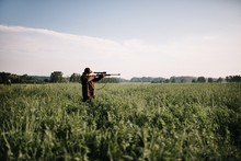Person Aiming With Gun Amidst Grass On Field