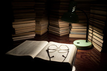 The Lamp And The Book On The Table. Reading A Book With Lighting The Lamp In The Dark. Books On Wooden Table Under Lamp Light