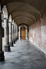  corridor inside courtyard and ancient columns at the end a old wood door.