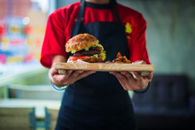 Waitress In Red Uniform Serving A Burger With French Fries