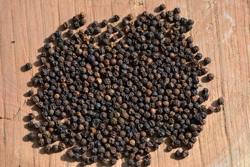  Black peppercorns on wooden background