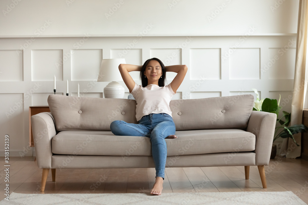 Vietnamese millennial girl rest on comfortable couch at home - obrazy, fototapety, plakaty 