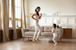 © fizkes - Happy young Asian mom and daughter dancing at home