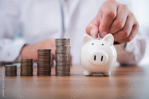 Fotografía businessman hand putting coins with piggy bank