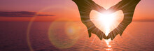 Two Hands In The Shape Of A Heart On A Sunset Background Over The Sea. The Concept Of A Romantic Date, A Declaration Of Love, A Love Relationship.