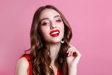 Close-up portrait of young beautiful girl.Perfect toothy smile. Red lips and perfect skin on pink background.