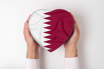 Wall Mural - Flag of Qatar on a heart shaped box in a male hands. White background