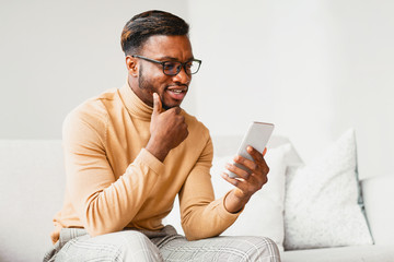 Canvas Print - Man Using Phone Browsing Internet Sitting On Couch At Home