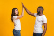 Joyful interracial sweethearts giving high-five to each other, clapping hands