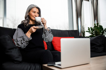 Wall Mural - Pleased woman smiling and enjoying coffee break stock photo