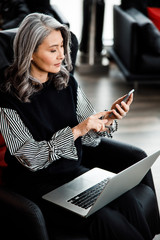 Wall Mural - Attentive woman using two gadgets at work stock photo