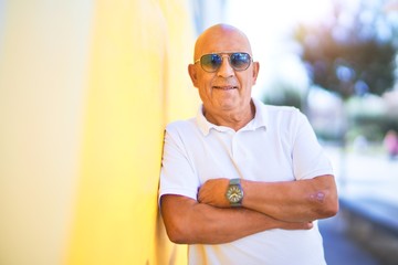 Wall Mural - senior handsome man smiling happy and confident. leaning on the wall wearing sunglasses with smile o