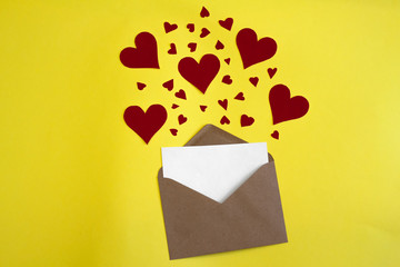 Red paper hearts fly out of craft paper envelope on the yellow background. Valentine day. love concept. Gift, message for lover. Space for text. Square banner