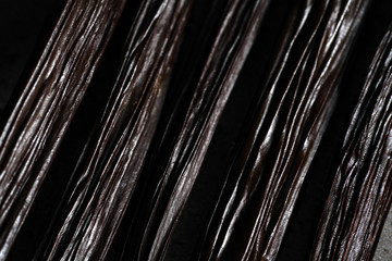 Closeup detail, dark brown vanilla beans on dark table, abstract gourmet background