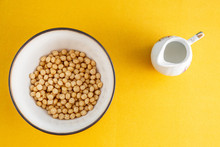 Honey Balls Of Different Cereals In A Deep Bowl And Milk On A Yellow Background