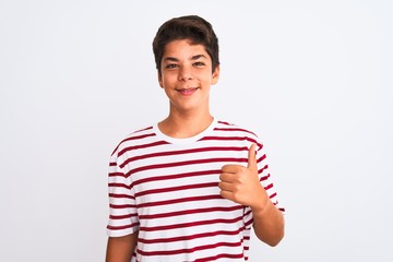 Handsome teenager boy standing over white isolated background doing happy thumbs up gesture with hand. Approving expression looking at the camera with showing success.